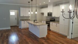 A kitchen with white cabinets and hardwood floors.