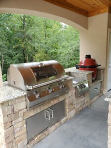 An outdoor kitchen with a grill and sink.